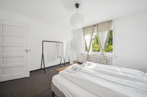 a white bedroom with a bed and a window at Dohlenweg 2 in Zürich