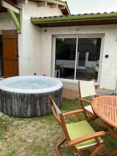- un bain à remous dans la cour avec deux chaises et une table dans l'établissement Charmant Studio - Jacuzzi/Jardin, à Andernos-les-Bains