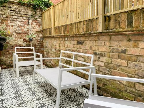 two white chairs sitting next to a brick wall at Stylish 3-bedroom home in Canterbury City-Centre - Superb Location! in Canterbury
