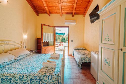 a bedroom with two beds and a door to a patio at Agriturismo Rocce Bianche - Bungalows in Arbus