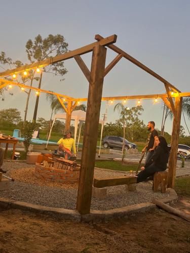 a group of people sitting on a bench under a tent at Container Suítes Recanto Monte Trigo in São Francisco do Sul