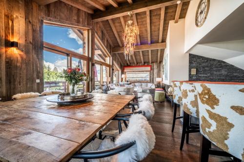 - une salle à manger avec une grande table et deux chiens assis dans l'établissement Chalet Purdey Combloux - BY EMERALD STAY, à Combloux