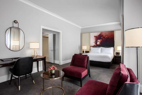 a hotel room with a bed and a desk and chairs at Waldorf Astoria Chicago in Chicago