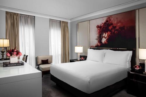 a bedroom with a white bed and a large painting at Waldorf Astoria Chicago in Chicago