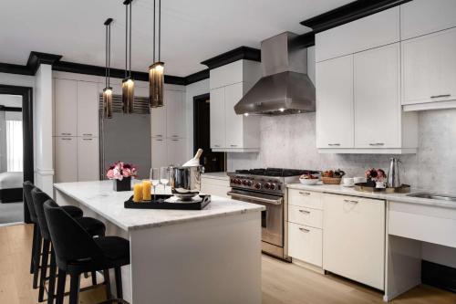 a kitchen with white cabinets and a kitchen island with chairs at Waldorf Astoria Chicago in Chicago