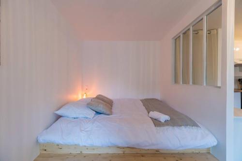 1 cama blanca en un dormitorio blanco con luz en Studio Cosy - plein coeur de Lannion, en Lannion