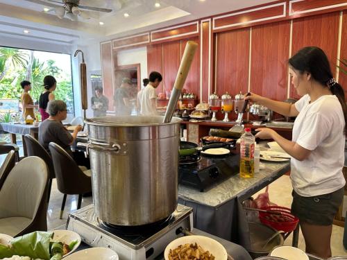 a woman standing in a kitchen preparing food at Confetti Garden Resort in Vang Vieng