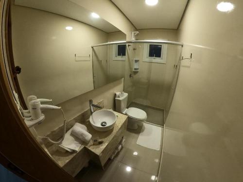 a bathroom with a sink and a toilet and a mirror at Nhtel Acomodações in Novo Hamburgo