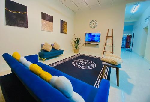 uma sala de estar com um sofá azul e uma televisão em SOFEA HOMESTAY em Pantai Cenang