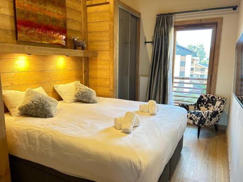 une chambre avec un lit avec deux pantoufles dessus dans l'établissement Appartement de Charme au Centre des Gets, 2 Chambres, Terrasse, Parking, Services Inclus - FR-1-623-348, aux Gets