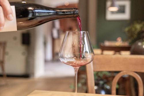 a person pouring wine into a wine glass at Aparthotel Ansitz Felsenheim in Lermoos