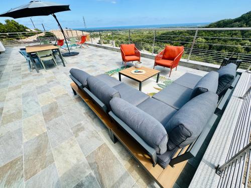 a couch sitting on top of a patio with an umbrella at "Villa Cavone" vue mer - piscine privée in Ventiseri