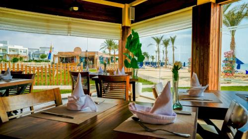 SeaVille Beach Hotel by Elite Hotels & Resorts في العين السخنة: مطعم بطاولات وكراسي وإطلالة على الشاطئ