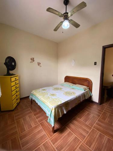um quarto com uma cama e uma ventoinha de tecto em Casa acolhedora e familiar em Campos dos Goytacazes