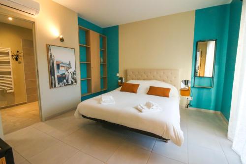 1 dormitorio con 1 cama blanca grande y paredes azules en Vita, Jacuzzi Partagé & Parking avec Borne de Recharge Voiture Electrique en Sarlat-la-Canéda