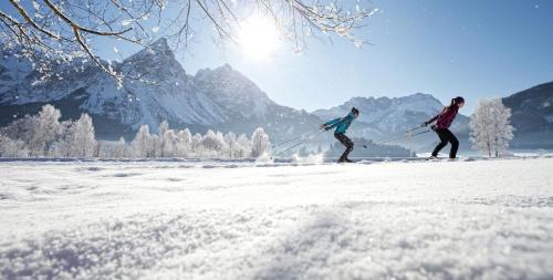 two people cross country skiing in the snow at Aparthotel Ansitz Felsenheim in Lermoos