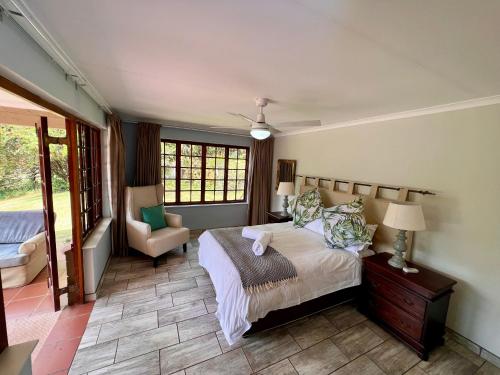 um quarto com uma cama e uma cadeira em Berg Escape Kiepersol - Spacious Luxury Family Home em Winterton