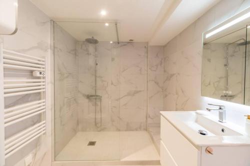 La salle de bains blanche est pourvue d'une douche et d'un lavabo. dans l'établissement Studio Cœur de Ville - Lannion, à Lannion