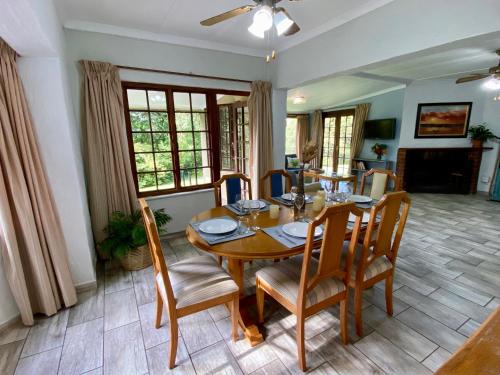 uma sala de jantar com uma mesa de madeira e cadeiras em Berg Escape Kiepersol - Spacious Luxury Family Home em Winterton