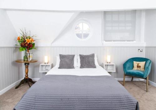 a bedroom with a large bed and a blue chair at The Townhouse Sutton in Sutton Coldfield