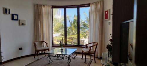 a living room with a table and a large window at English Point Residence Beach Apartments Mombasa in Mombasa
