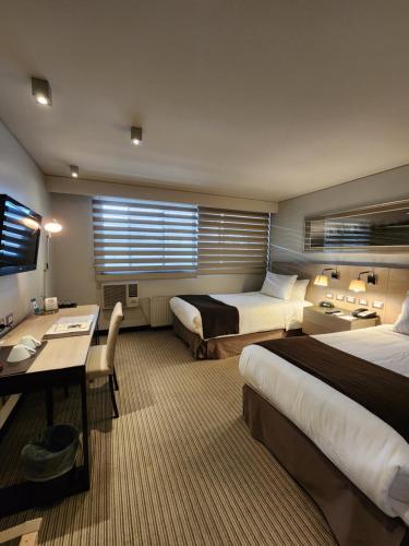 a hotel room with two beds and a desk at Hotel Los Españoles Plus in Santiago