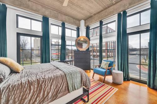 a bedroom with a bed and large windows at Charming 1BR Condo - Full Kitchen - Uptown Living in Charlotte