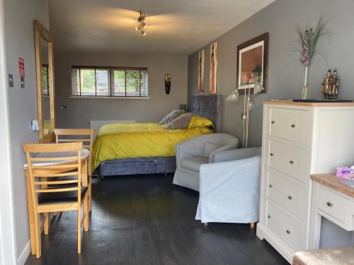 a bedroom with a bed and a table and a chair at Twin Gates Annexe in Falmouth