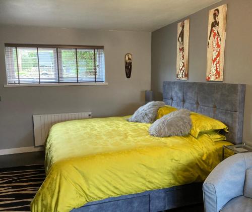a bedroom with a large bed with a yellow blanket at Twin Gates Annexe in Falmouth