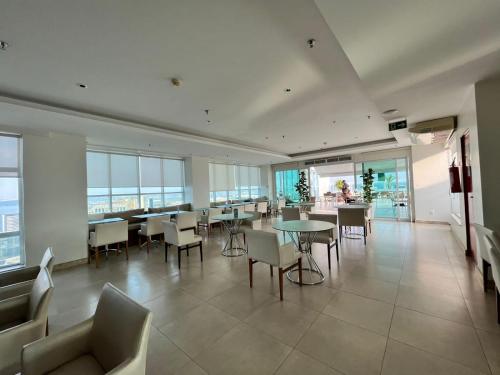 a large room with tables and chairs and windows at Quarto de Luxo - Saint Moritz in Brasília