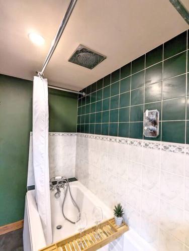 a bathroom with a tub and a green tiled wall at 3-Bed, Sleeps 6, 1 Bath, Parking, WiFi in Shalford