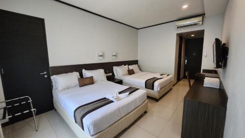 a hotel room with two beds and a television at Summer Hills Hotel & Villas Bandung in Bandung