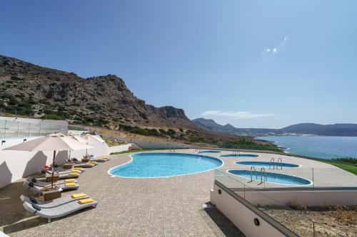 een groep zwembaden met parasols en het water bij Beachfront Villa Atalandia with Heated Pool, Gym, BBQ & Office in Goúdhouros