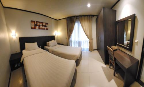 a hotel room with two beds and a television at Summer Hills Hotel & Villas Bandung in Bandung