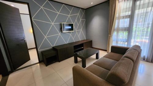 a living room with a couch and a tv at Summer Hills Hotel & Villas Bandung in Bandung
