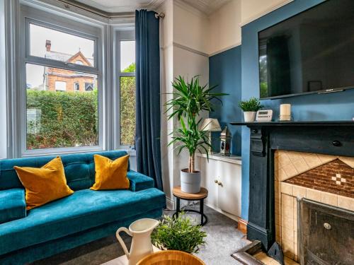 a living room with a blue couch and a fireplace at Gorgeous 4 Bedroom Home 7 Min from City Centre - Pass the Keys in Belfast