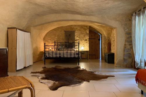 Cette chambre comprend un lit dans un mur en pierre. dans l'établissement Appartement dans ancien mas rénové avec piscine partagée ouverte de 9h30 à 11h30 et de 16h30 à 18h30, à Bessas