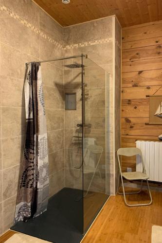La salle de bains est pourvue d'une douche en verre et d'une chaise. dans l'établissement Appartement dans ancien mas rénové avec piscine partagée ouverte de 9h30 à 11h30 et de 16h30 à 18h30, à Bessas