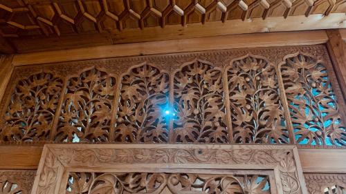 a blue light shines through the ornate carving on a wooden door at House Boat New Lucifer in Srinagar