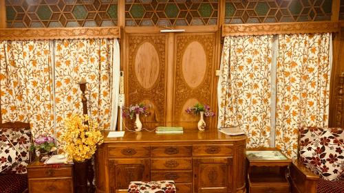 a room with curtains and a wooden dresser with flowers on it at House Boat New Lucifer in Srinagar