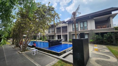 a man sitting in front of a house with a swimming pool at Summer Hills Hotel & Villas Bandung in Bandung