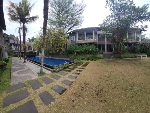 a house with a swimming pool in front of a yard at Summer Hills Hotel & Villas Bandung in Bandung