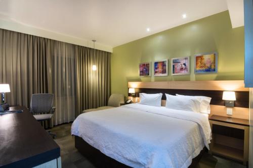 a hotel room with a large bed and a chair at Hampton Inn by Hilton Silao-Aeropuerto, Mexico in Silao