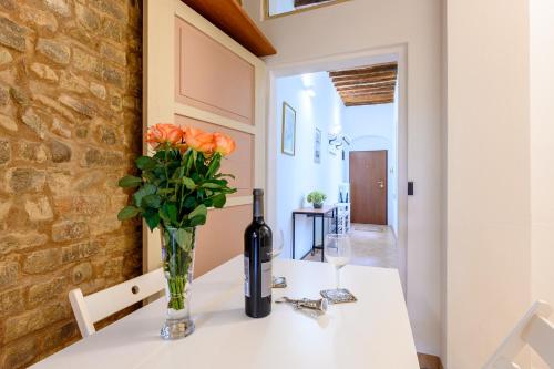 a table with a bottle of wine and flowers on it at Parma Parco Ducale Cozy Apartment in Parma