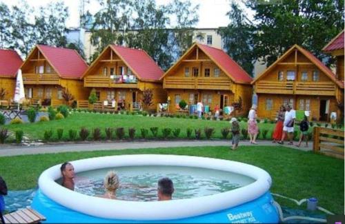 a group of people in a pool in front of a house at Tropicana Ϫϫ Holiday Houses in Jastrzębia Góra
