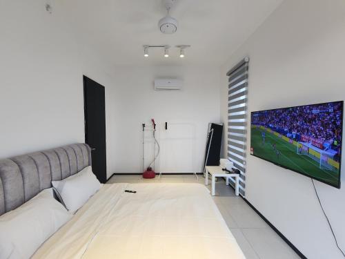 a living room with a couch and a tv on a wall at Urban Suite - George Town in Jelutong