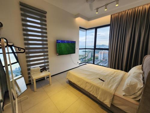 a bedroom with a bed and a flat screen tv at Urban Suite - George Town in Jelutong