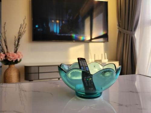 a blue glass bowl on a table with a remote control at Urban Suite - George Town in Jelutong