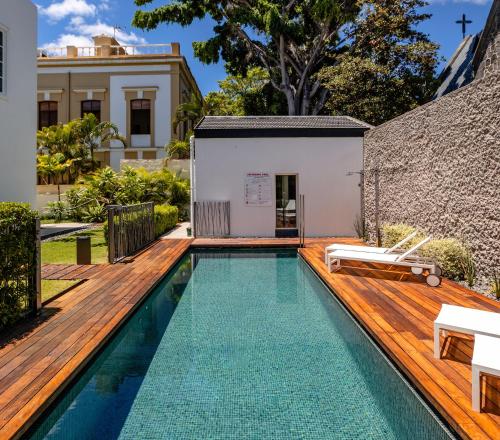 a swimming pool with a wooden deck and a house at The Park Suites in Santa Cruz de Tenerife