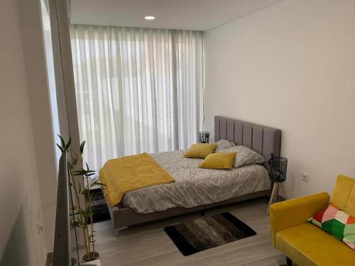 a bedroom with a bed with yellow sheets and a window at Oliver Beach House in Poço da Cruz